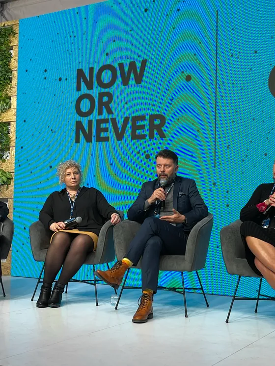 Rafał Szymański speaking into a microphone during the debate on child psychiatry at the Economic Forum in Karpacz, with Marta Golbik sitting next to him