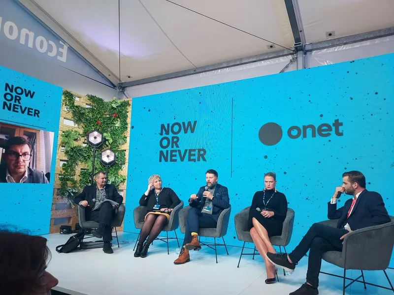 Onet's stage at the Economic Forum in Karpacz: five people in armchairs in front of a blue screen with the words Now or Never and Onet, on the left a screen showing the participant joining remotely