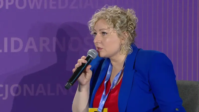 Marta Golbik in a blue jacket speaking into a microphone on the stage at Campus Polska Przyszłości