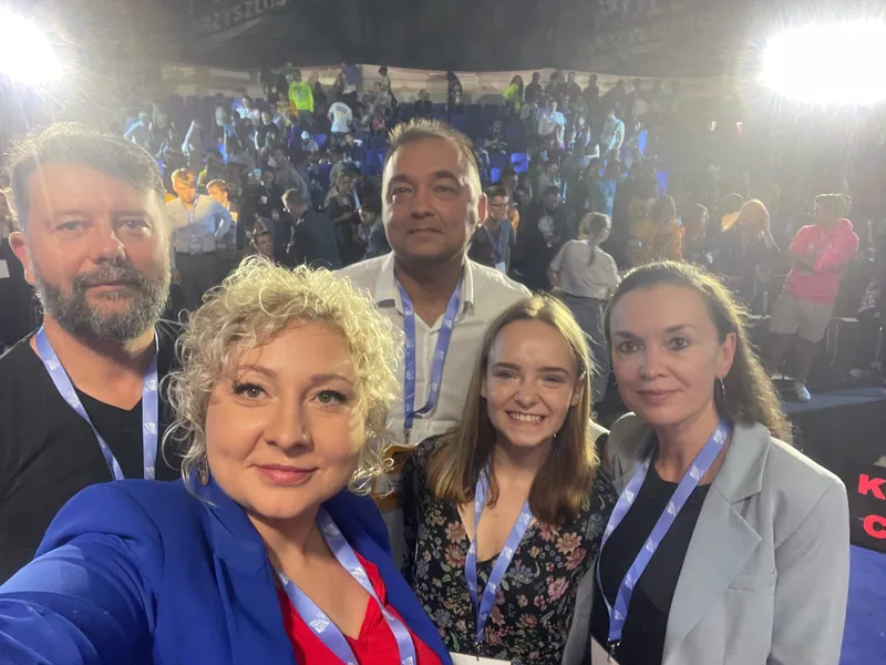 A selfie of the five debate participants on the stage of Campus Polska Przyszłości, with the audience getting up from their seats in the hall behind them