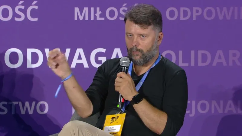 Rafał Szymański speaking into a microphone and gesturing with his hand, seated on the stage at Campus Polska Przyszłości