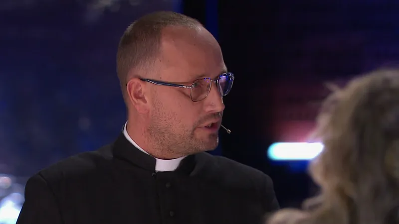 Ks. Tomasz Trzaska w koloratce mówi przy stole w studiu programu Hala odlotów