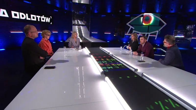 Studio programu Hala odlotów w TVP: sześć osób siedzi przy długim białym stole, w tle niebieskie światła i neonowe oko